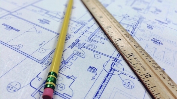 Close-up of a blueprint with a pencil and wooden ruler.