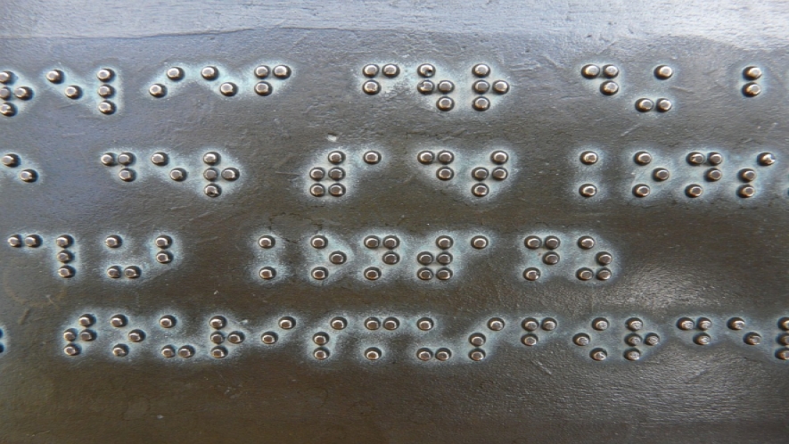 A photo of metal plate with braille on it. 