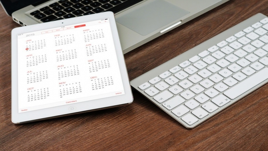 A photo of an iPad with a calendar open and a desktop keyboard. 