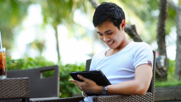 A photo of a man looking at an iPad and smiling. 